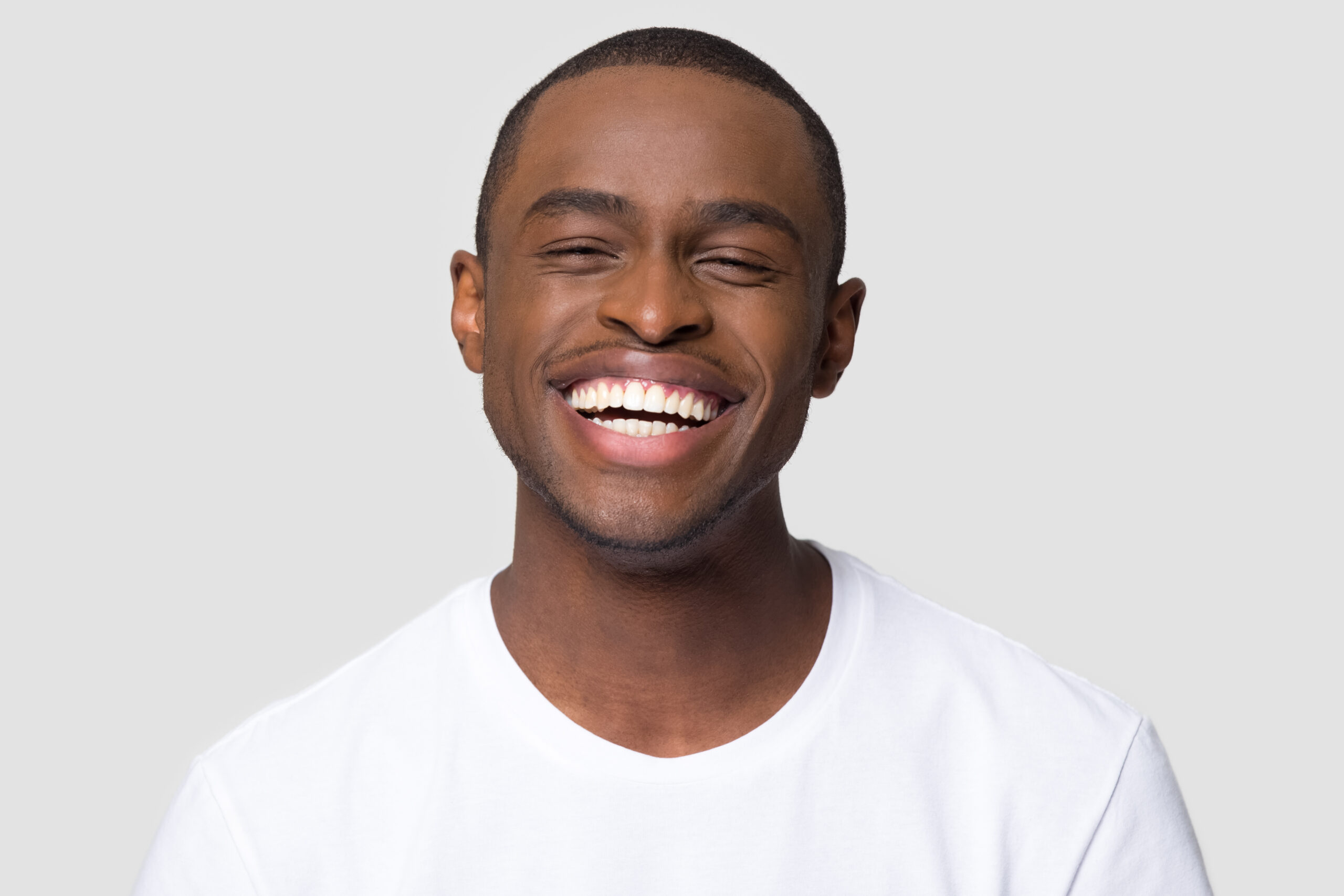 Adult man with bright white smile laughing with his eyes closed