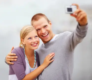 A young couple smiling for a photo on vacation after teeth whitening treatments in Fort Collins.